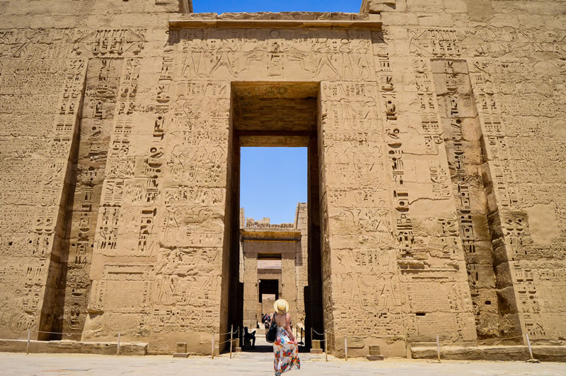 primer-plano-de-una-mujer-de-pie-delante-de-un-templo-de-medinet-habu-en-egipto